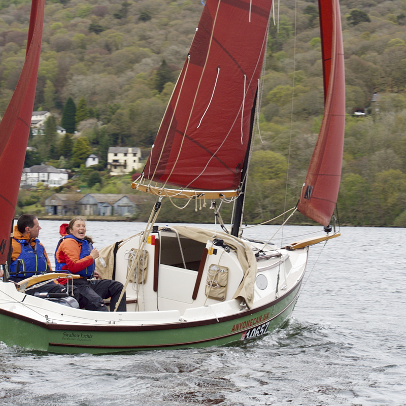Large sailng dingy sails into towering clouds.