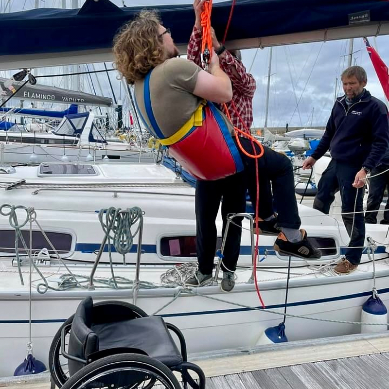 Gent rises on hoist from chair onto boat