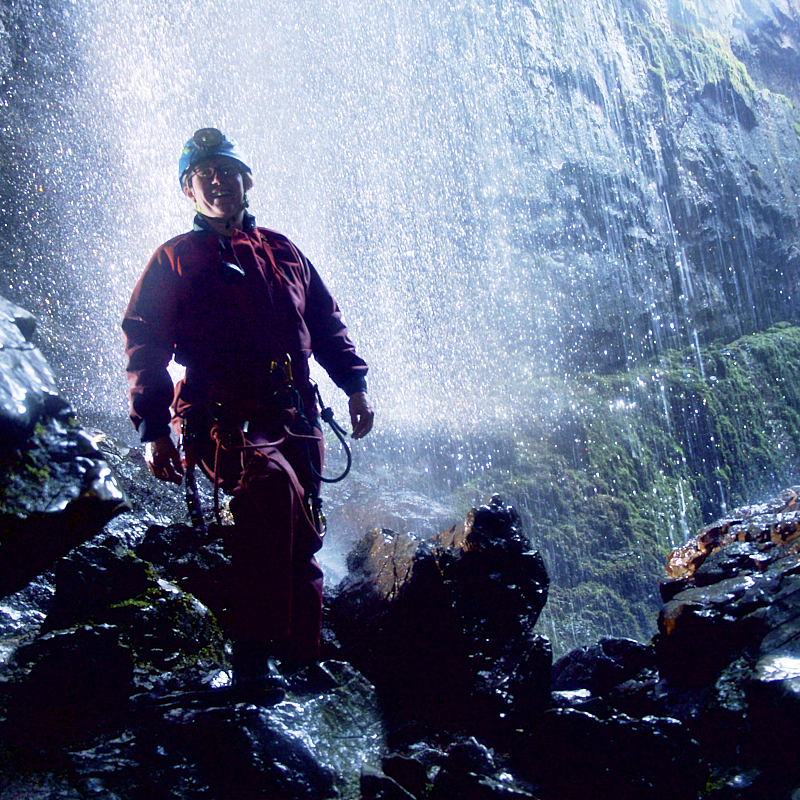 Caver in fron of waterfall 