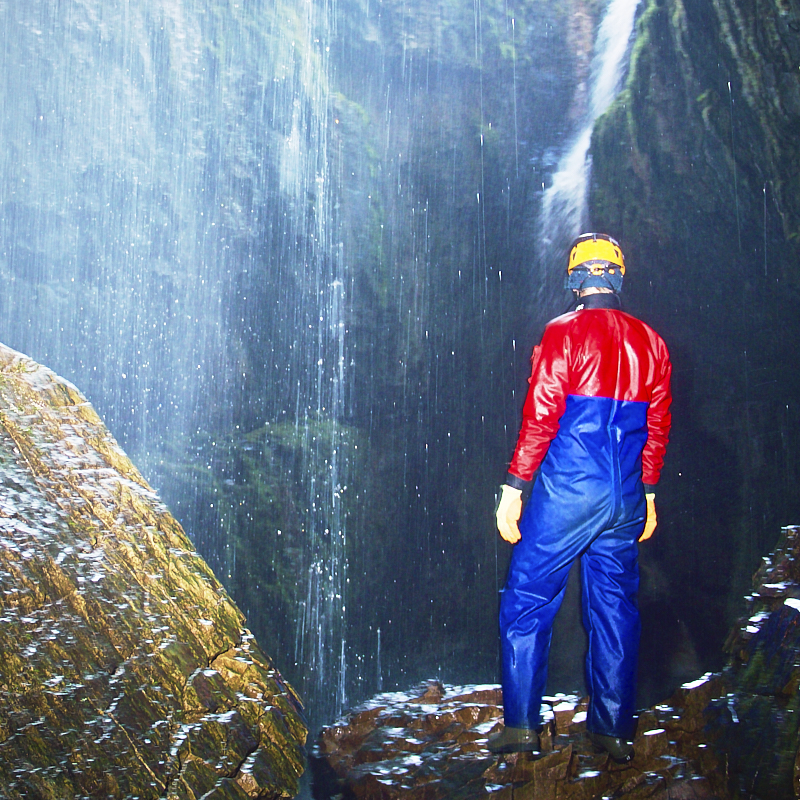 caver stares into waterfall with light comming from behind