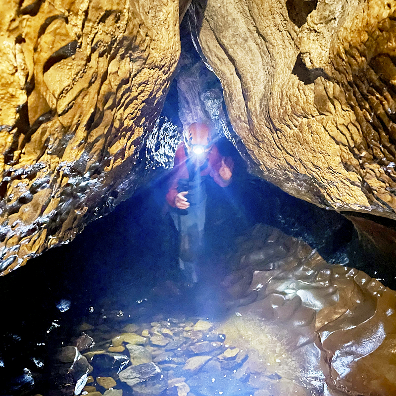 Man holds up fire cooked pizza.