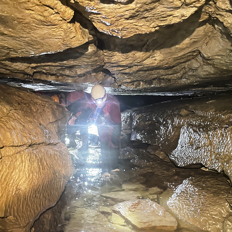 Caver ducks to travel along low passage