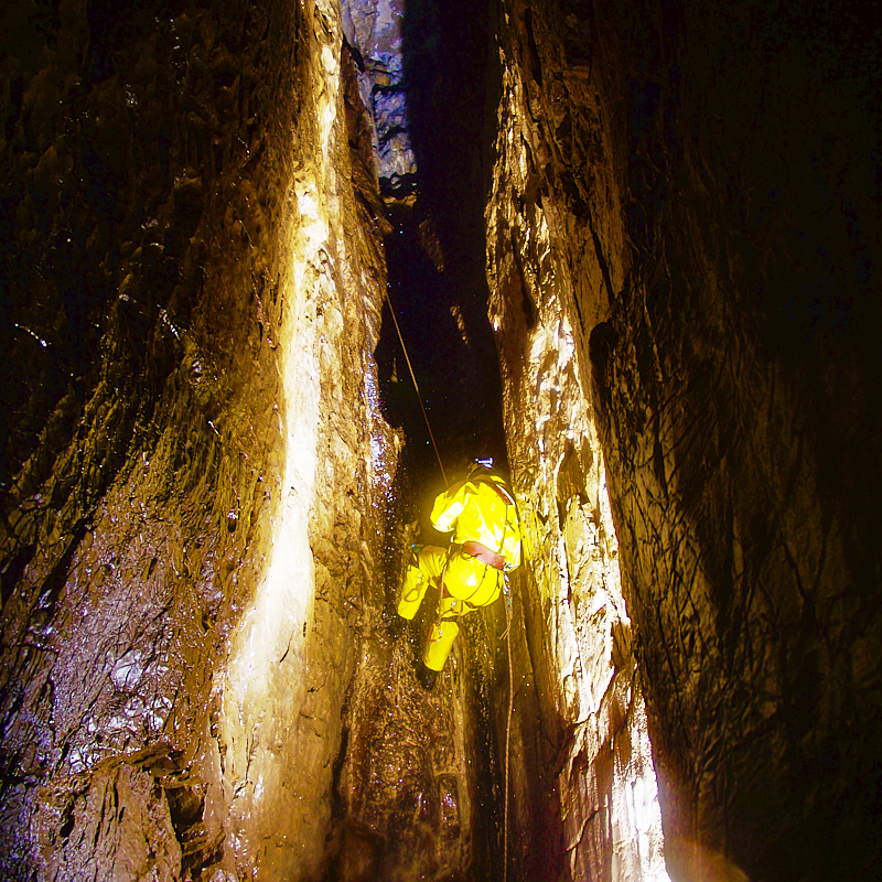 Caver abseils down a tight passage
