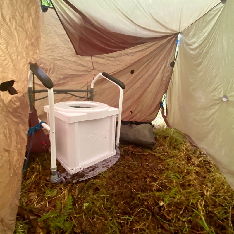Portable toilet in. tent with handrails