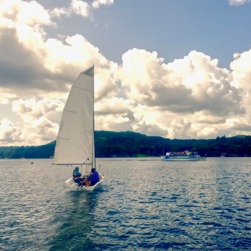 Large sailng dingy sails into towering clouds.