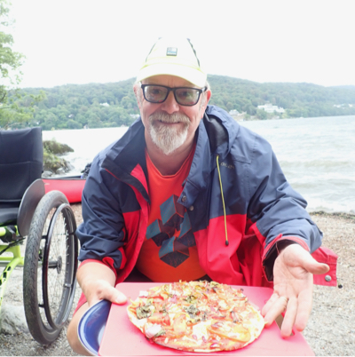 Man holds campfire pizza (very proud)