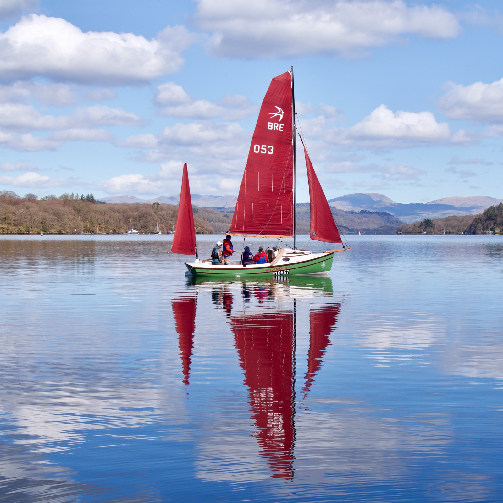 Bright day with green boat on red sails