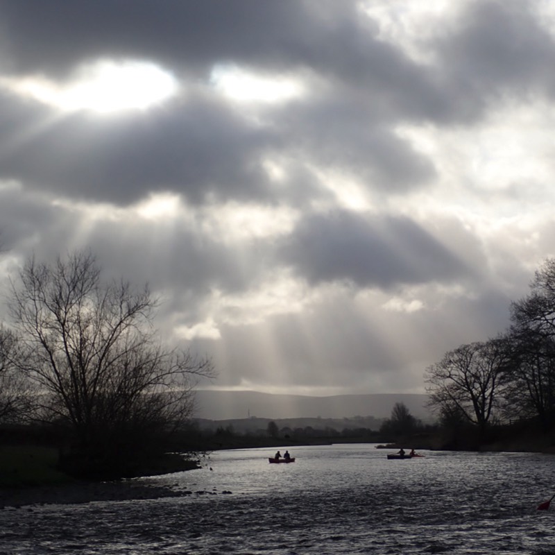 Canoists in distance under sunbeams 